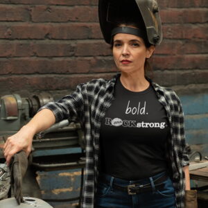 bold-ROCKstrong-woman-repairing-her-motorcycle-black-tshirt-31798_1500x1500 Women with welding helmet in front of motorcycle wearing ROCK Fashion brand t-shirt with statement bold ROCKstrong