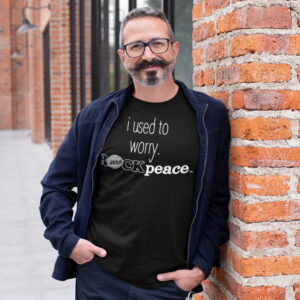 i-used-to-worry-ROCKpeace-black-t-shirt-man-leaning-brick-wall-31715_2000x2000 Man standing against brick wall wearing a ROCK Fashion brand t-shirt with statement I used to worry ROCK peace